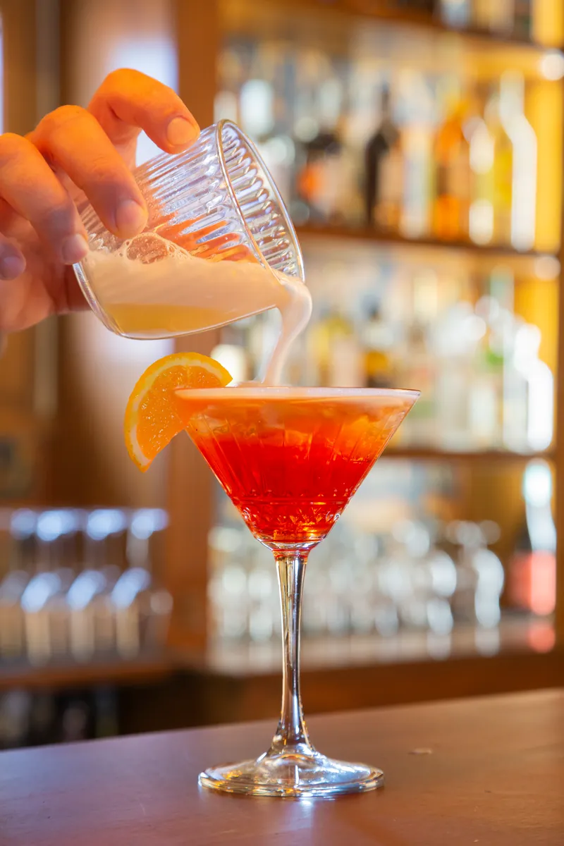 La schiuma versata su un cocktail rosso nella coppa