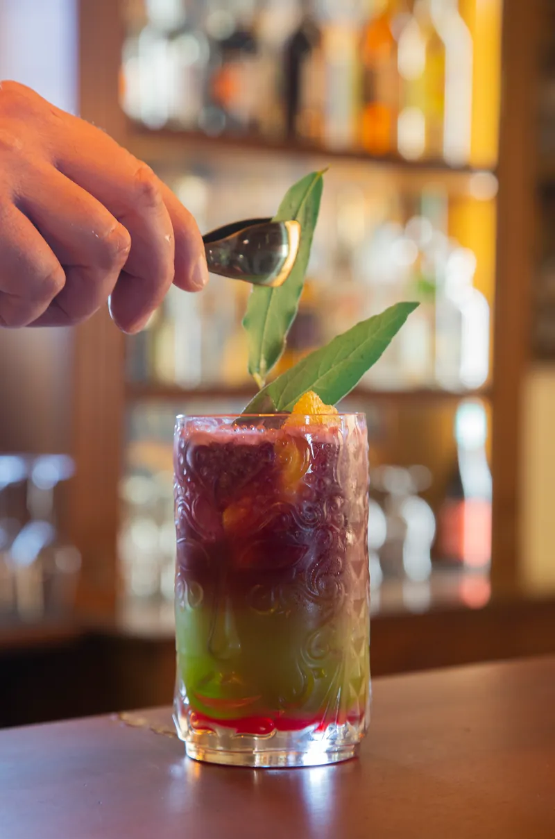 Il barman posa una foglia di salvia sul cocktail
