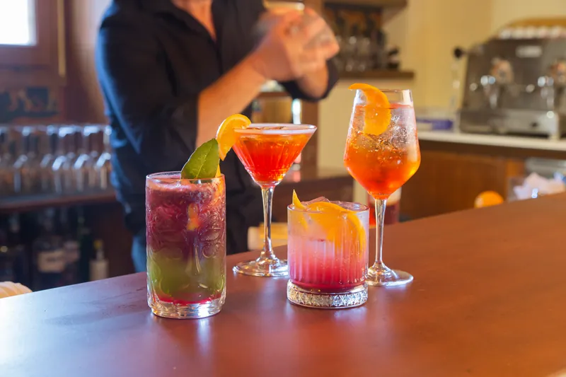 Il barman prepara un cocktail dietro tre bicchieri pronti sul bancone