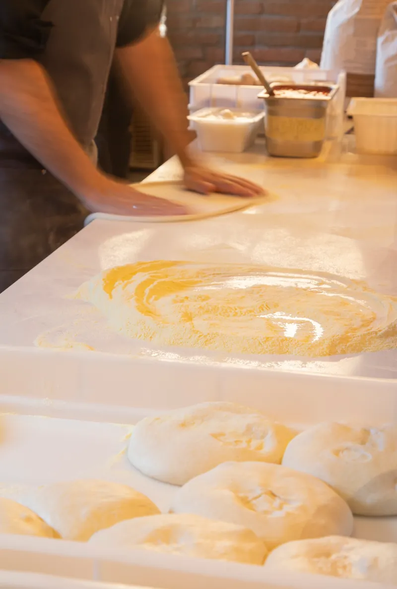 Le mani del pizzaiolo stendono l'impasto